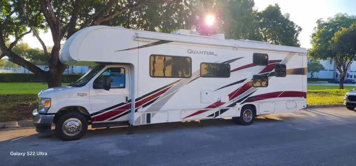 Beautiful white Quantum SE Class C motorhome, with stylish red and grey accents, available for rv rental. Parked on a sunny day.. Thor Quantum 2021
