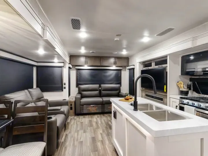 Spacious, modern RV rental interior: living area with recliners, kitchen island with sink, and dining space.. Jayco Eagle 2024