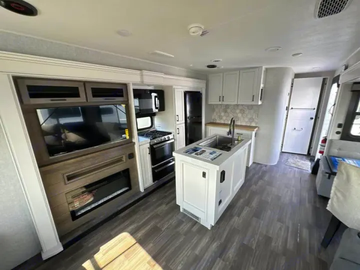 Clean rv rental interior featuring a full kitchen with island, living area with TV & fireplace.. Jayco Eagle 2024