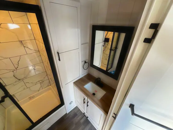 Sleek RV rental bathroom featuring a marble-style shower, modern vanity with black hardware, and crisp white cabinetry.. Jayco Eagle 2024