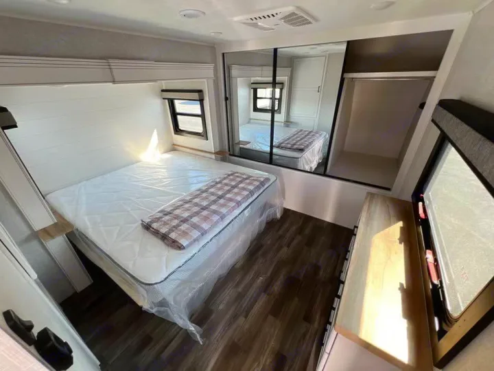 Clean RV rental bedroom with a queen bed, mirrored closet, and window for comfortable travel.. Jayco Eagle 2024