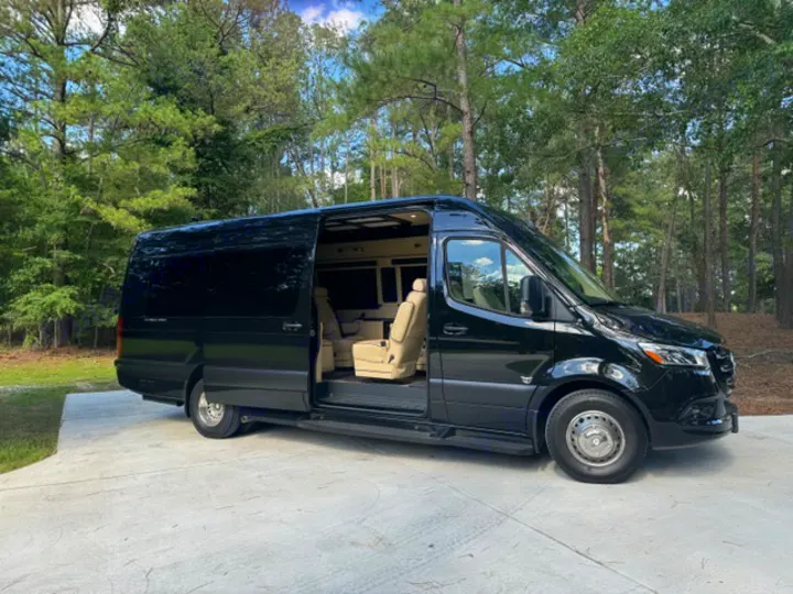 Luxury black Mercedes-Benz Sprinter rv rental van. Side door open revealing plush tan seating, ready for adventure.. Ultimate Toys Ultimate Coach 2024