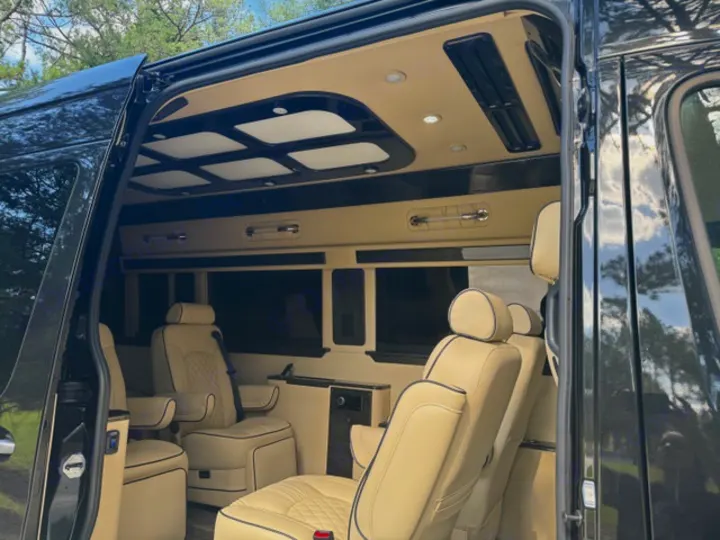 Inside a luxurious custom van rv rental, showcasing cream leather seating, a custom ceiling, and plush interior.. Ultimate Toys Ultimate Coach 2024