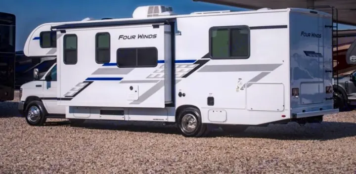 White Four Winds Class C rv rental, slide-out extended. Side view of the recreational vehicle on gravel, ready for travel.. Four Winds 28z 2027