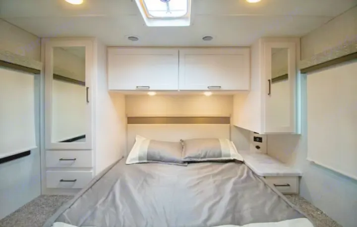 RV rental bedroom: a cozy bed with modern overhead cabinets, mirrored side closets, and a skylight for comfort.. Four Winds 28z 2027