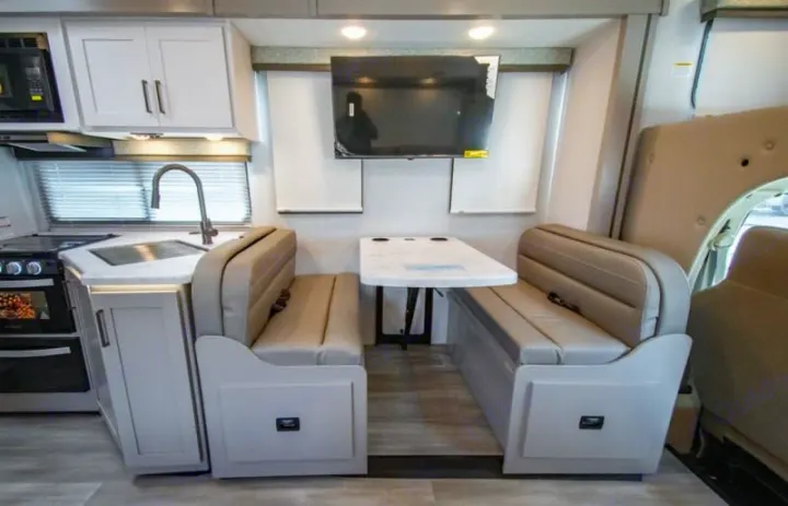 RV rental interior featuring a modern kitchen with stove/sink and a comfortable dinette with a table and TV.. Four Winds 28z 2027