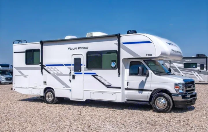 White Thor Four Winds Class C motorhome rv rental on gravel, under blue sky, ready for travel adventures.. Four Winds 28z 2027
