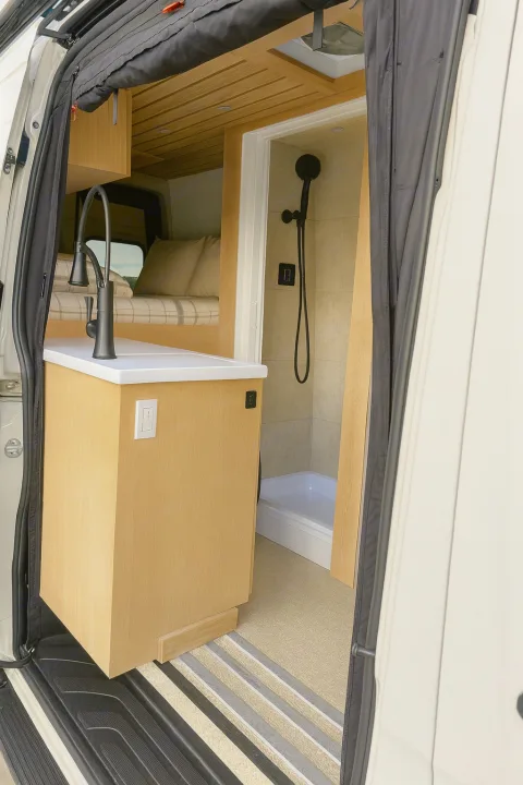 RV rental: Modern van interior features a compact kitchen, comfortable bed, and full shower, ideal for travel.. MERCEDES-BENZ Sprinter 2500 AWD 2024