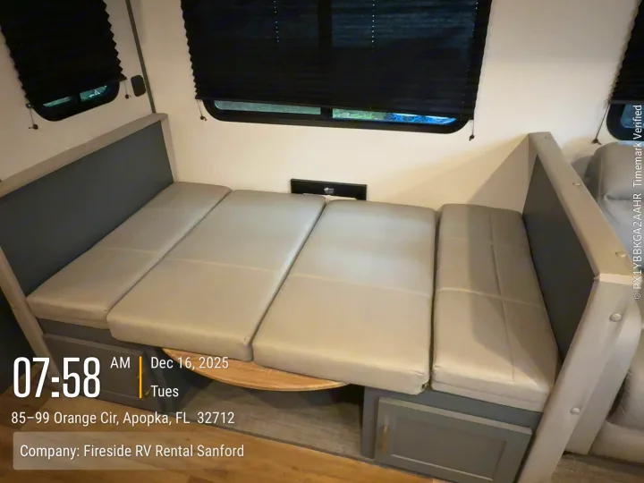 RV rental dinette converted into a comfortable bed with light cushions, viewed inside the spacious interior.. Keystone Bullet 2022