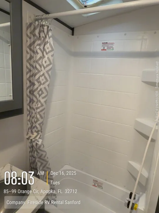 Fireside RV rental shower: Clean, compact stall with a gray chevron curtain and built-in shelves, ready for your trip.. Keystone Bullet 2022