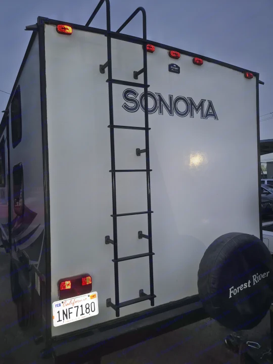 Rear of a Sonoma Forest River RV rental with illuminated lights, California plate 1NF7180, and a ladder.. Forest River Sonoma 2020