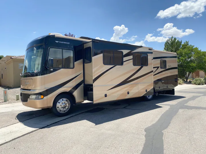 A stylish, multi-toned Fleetwood motorhome for rv rental, parked on a sunny day with an extended slide-out for spacious travel.. Fleetwood Fiesta LX 2008