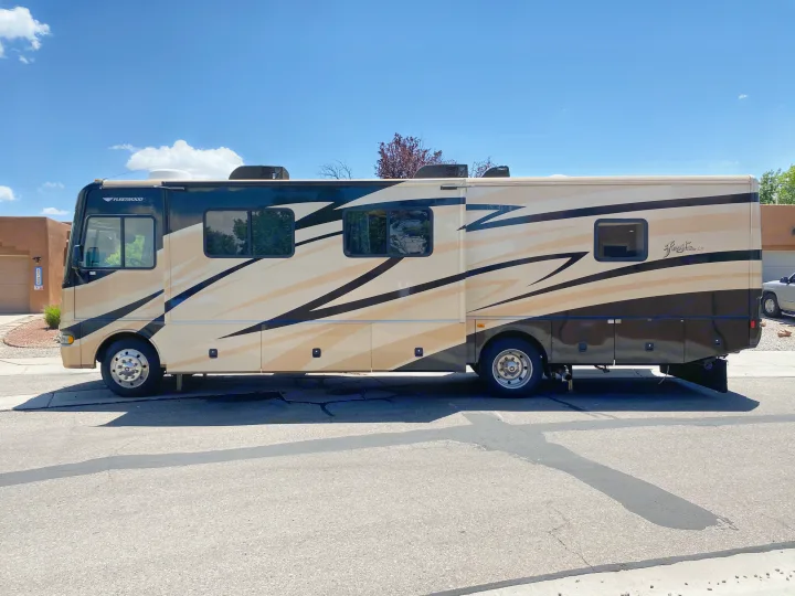 Fleetwood RV rental with beige and black design parked on a sunny street, ready for travel.. Fleetwood Fiesta LX 2008