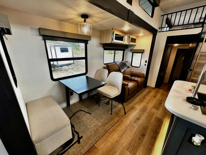 Modern RV rental interior: cozy living space with dinette, plush recliners, and loft. Perfect for travel adventures.. Forest River Puma Destination 2026