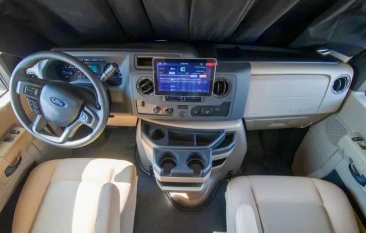 RV rental interior: Driver's cockpit with Ford steering wheel, central touchscreen, and spacious seating.. thor four winds 2027
