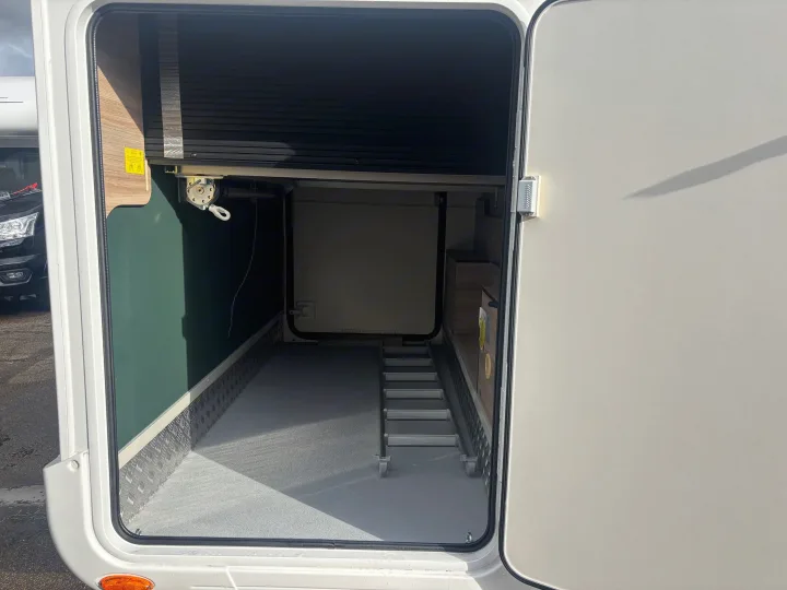 Spacious RV rental storage compartment, featuring portable stairs, textured floor, and diamond plate trim for gear.. FORD TRANSIT RIMOR KILIG 669 5 BERTH 2026
