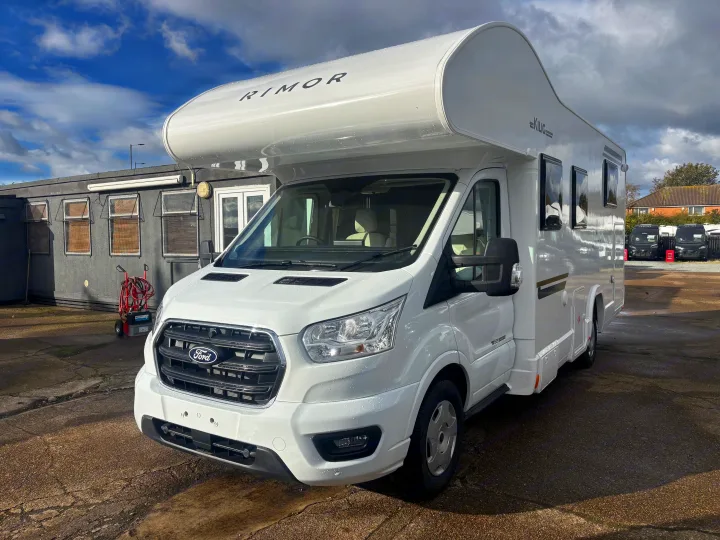 Sleek white Rimor motorhome on a Ford chassis, parked outdoors. Discover your perfect rv rental for memorable road trips.. FORD TRANSIT RIMOR KILIG 669 5 BERTH 2026