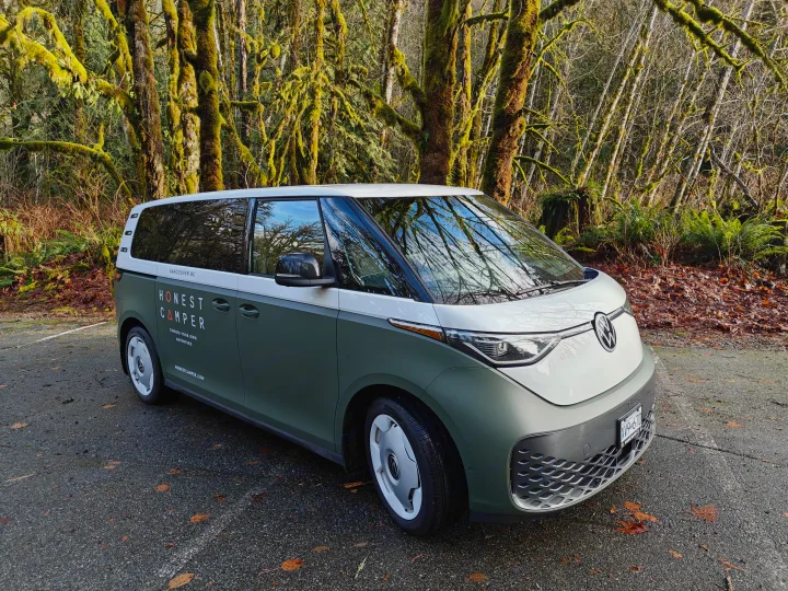 This two-tone VW ID. Buzz by Honest Camper, an RV rental, is parked near moss-covered trees in Vancouver, BC.. Volkswagen ID. Buzz 2025