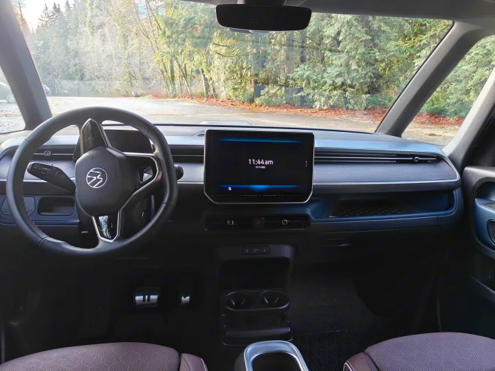 Inside a modern RV rental: driver's view of the dashboard, steering wheel, and central infotainment screen displaying 11:44 am.. Volkswagen ID. Buzz 2025