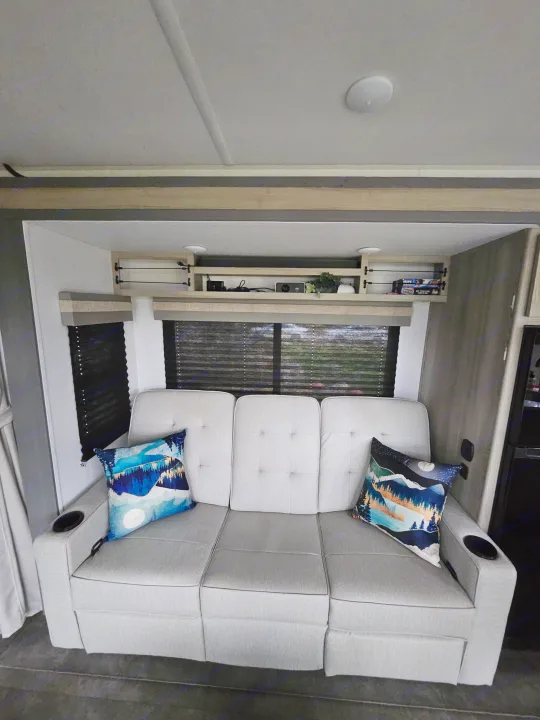Relax in this RV rental's comfy three-seat sofa with cup holders, scenic pillows, and an entertainment projector.. Forest River Wildwood FSX Platinum 2023