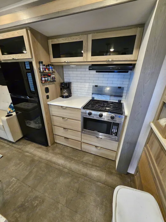 This modern RV rental kitchen features a stove, oven, microwave, and ample storage, perfect for comfortable travels.. Forest River Wildwood FSX Platinum 2023