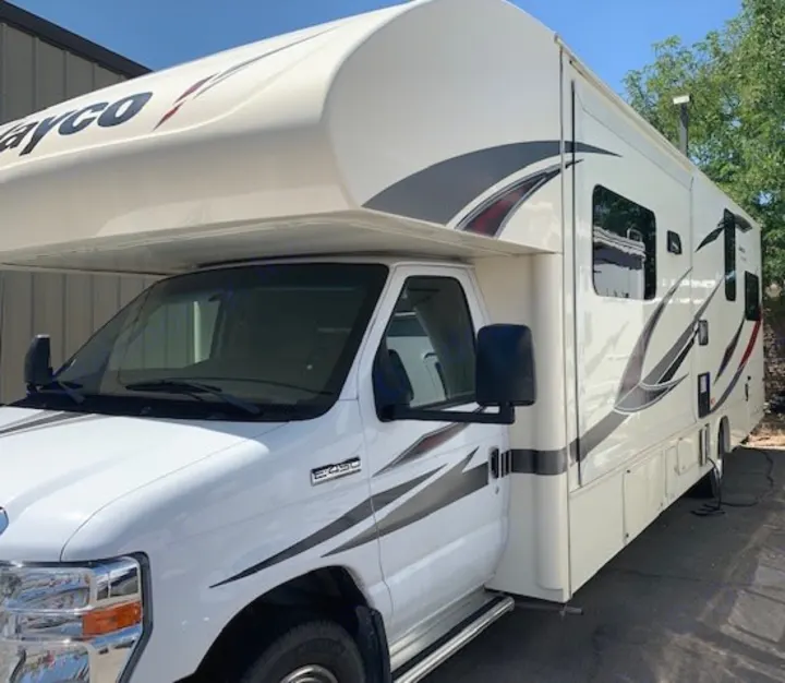 This bright white Class C Jayco RV rental, featuring gray and red graphics, is parked on a sunny day.. Jayco Redhawk 31X 2017