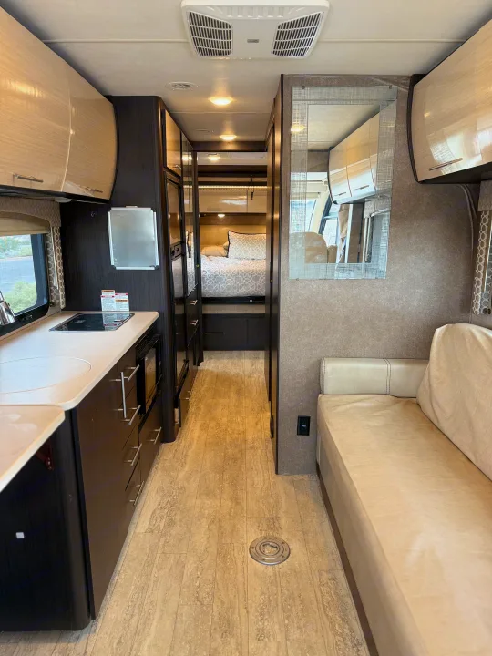Inside an **rv rental**, this view highlights the kitchen, living area with a sofa, and hallway leading to the bedroom.. Thor Axis 2018