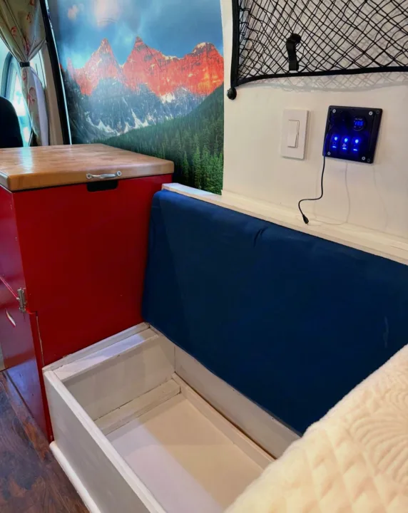 RV rental interior: open storage bench, red cabinet, mountain mural, and illuminated control panel with switches.. Ram Promaster 2500 2019