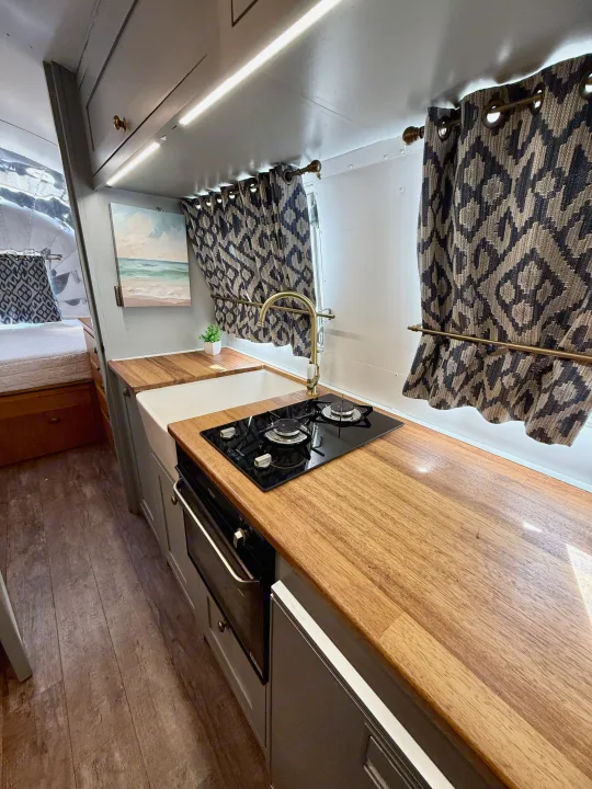 RV rental: Stylish galley with wood countertops, sink, two-burner stove, oven & cozy sleeping area.. Airstream overlander 2018