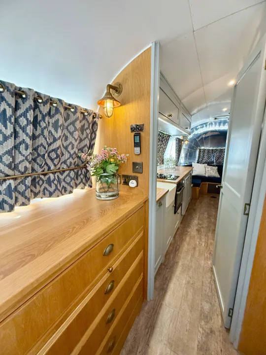 Experience cozy living in this beautifully renovated **rv rental**, featuring a full kitchen, patterned curtains, and custom cabinetry.. Airstream overlander 2018