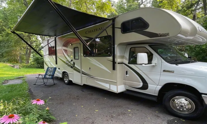 Thor Chateau Class C rv rental with extended awning & chair, parked for a relaxing outdoor stay amid green trees.. Thor Motor Coach Chateau 2017