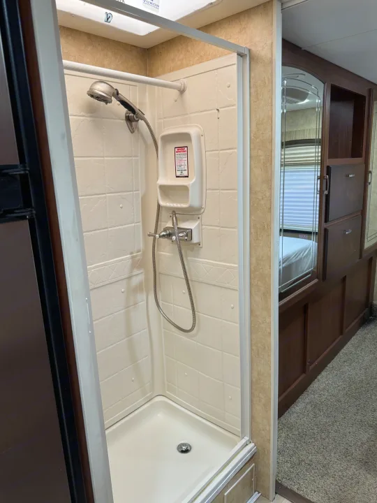 Clean and compact shower in an RV rental, with handheld sprayer and mirrored cabinetry reflecting the bedroom.. Jayco Melbourne 2012
