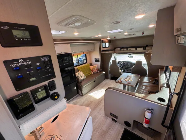 Spacious RV rental interior featuring a dinette, lounge, kitchenette, and various control panels for solar, generator, and climate.. Forest River Coachmen Freelander 2026