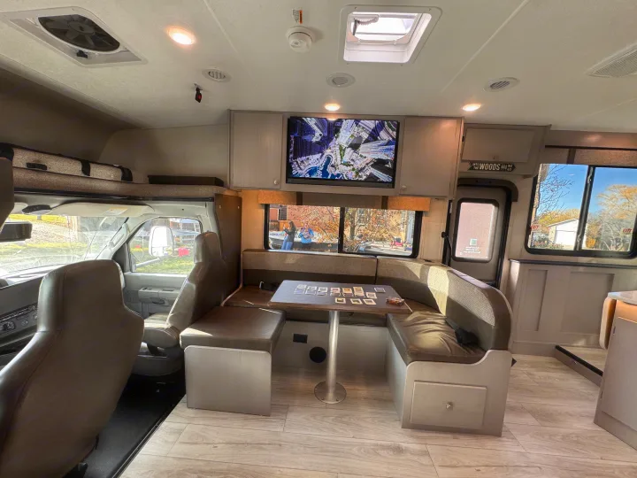 Inside a cozy rv rental, showing the dinette, TV, and cockpit. A game is on the table, ready for fun.. Forest River Coachmen Freelander 2026