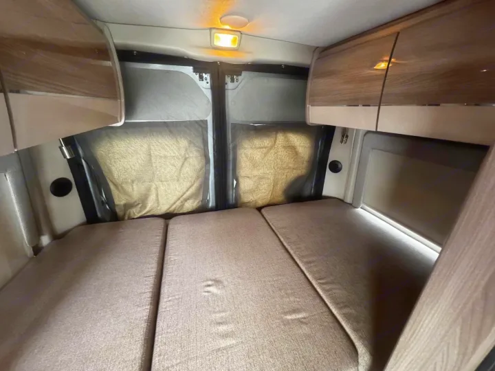 Experience comfort in this **rv rental** interior: a fold-out bed, overhead storage, and screened rear windows for privacy.. Thor Scope 2023