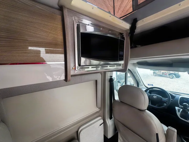 RV rental with a sleek, built-in microwave, modern wood-grain cabinetry, and comfortable driver's seat.. Thor Scope 2023