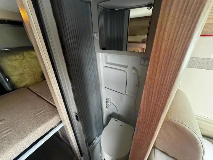 Explore this RV rental's compact interior: a functional bathroom with toilet, mirror, and shower, plus a cozy bunk bed.. Thor Scope 2023