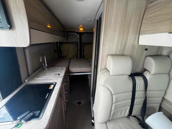 Explore the cozy interior of an rv rental: a kitchenette, convertible bed, and passenger seating ready for your next road trip.. Thor Scope 2023