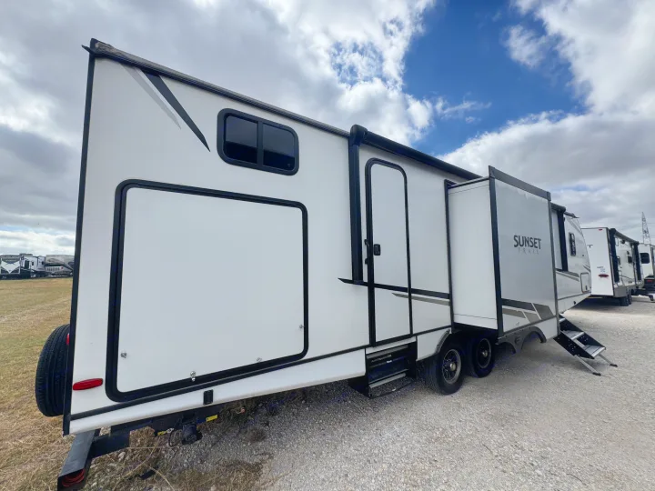 Clean white 'Sunset Trail' travel trailer, featuring a slide-out, window, and main entry, parked on gravel, ideal for your RV rental.. Crossroads RV Sunset Trail Super Lite 2022