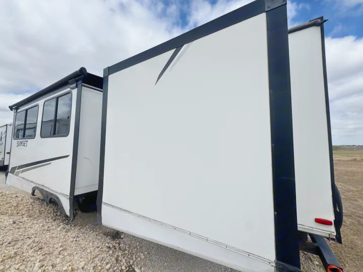 White Sunset Trail rv rental with extended side slide-out, showing its exterior, awning, and windows on a gravel lot.. Crossroads RV Sunset Trail Super Lite 2022