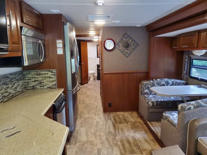 This rv rental interior features a functional kitchen with a microwave, a cozy dinette, and a clear hallway leading to the bathroom.. Georgetown Georgetown Motorhome 2016