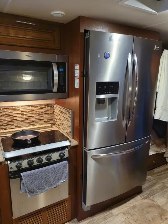 Modern RV rental kitchen showcasing stainless steel appliances: fridge, microwave, and induction cooktop with skillet.. Georgetown Georgetown Motorhome 2016
