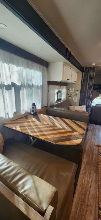 This RV rental features a bright dinette area with a unique chevron wood table, comfortable seating, and sheer curtains.. Jayco Redhawk 2017