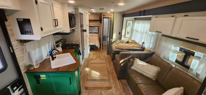 Spacious, modern rv rental interior with a bright kitchen, cozy living/dining area, and a glimpse of the bedroom.. Jayco Redhawk 2017