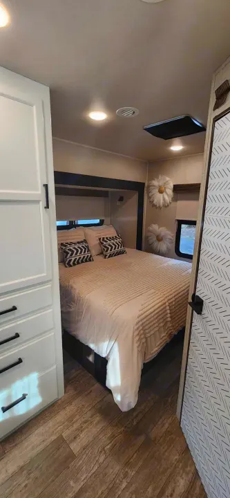 This cozy rv rental bedroom offers a comfortable bed, patterned pillows, and practical storage in a stylish interior.. Jayco Redhawk 2017