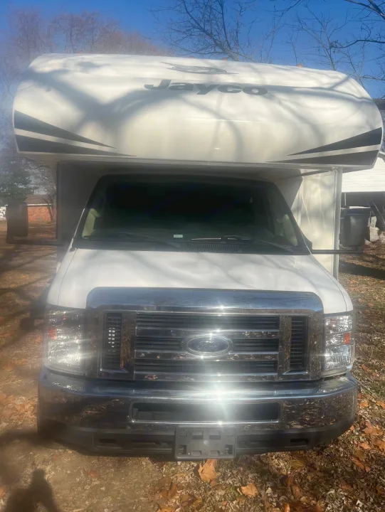 White Jayco RV rental with a Ford front, chrome grille, and shiny bumper, parked outdoors under a blue sky.. Jayco Redhawk 2019