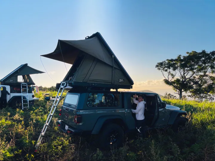 Adventure camping with an RV rental! Two Jeeps, equipped with rooftop tents, are set in a scenic outdoor landscape with a man.. Jeep Gladiator 2022