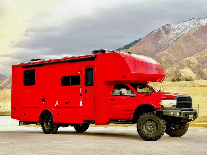 This rugged red DYNAMAX expedition RV, perfect for off-road rv rental adventures, is ready for mountain camping.. Dynamax ISATA 5 Explorer Extreme Package 2026