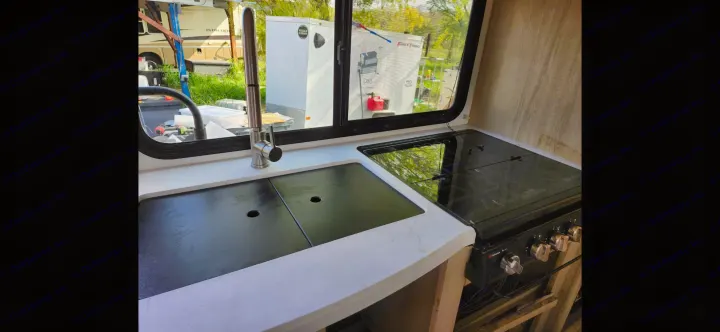 RV rental kitchen featuring a sleek sink, modern faucet, and stovetop beside a window with an outdoor view.. Winnebago Minnie Winnie 2025