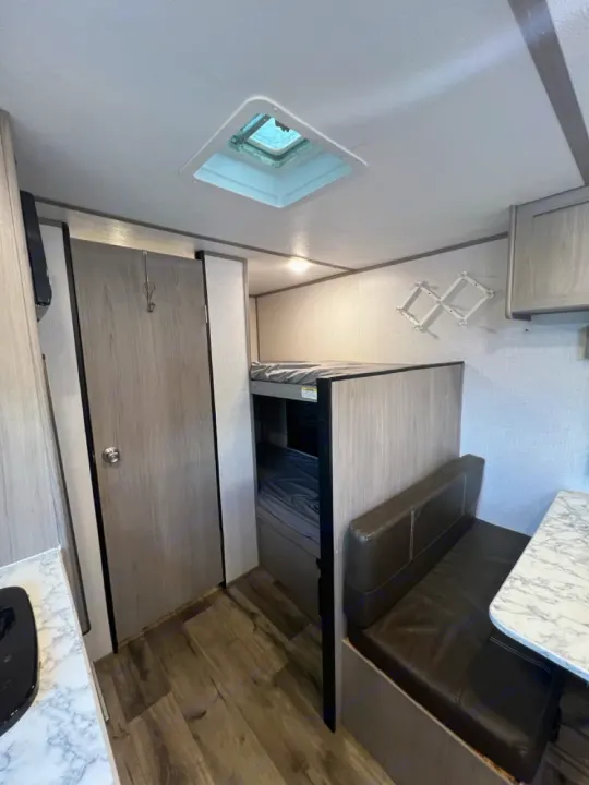 Compact RV rental interior with bunk beds, dinette, and kitchen area. Perfect for travel adventures.. Coleman Coleman 2023